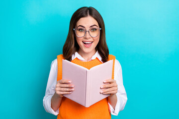 Photo of positive impressed cheerful woman with bob hairstyle orange waistcoat hold interesting book isolated on teal color background