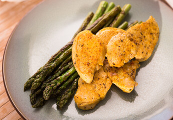 fried chicken breast pieces with asparagus on plate
