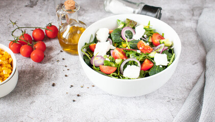 
Green vegan salad from a mixture of green leaves and vegetables. On a gray background
