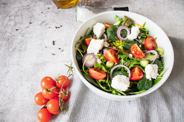 
Green vegan salad from a mixture of green leaves and vegetables. On a gray background