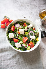 
Green vegan salad from a mixture of green leaves and vegetables. On a gray background