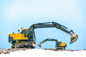 Еxcavator is working on earthmoving works in a sand quarry in winter. Two еxcavators dig sand and...