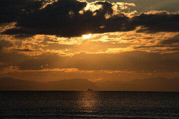 Fototapeta premium 海の水平線に浮かぶ船と夕焼け