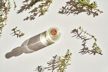 A bottle of thyme essential oil with fresh thyme on white background