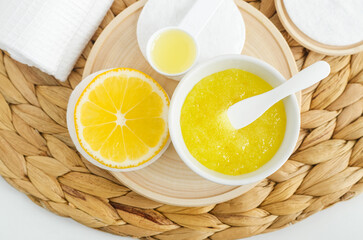 Fototapeta na wymiar Homemade lemon sugar scrub in a small white bowl. Natural beauty treatment and spa recipe. Top view, copy space.