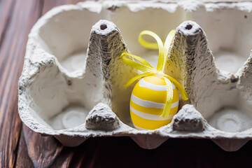 Easter eggs in egg carton. Yellow decorated Easter egg in an empty egg tray on a table in the kitchen
