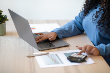 Fototapeta premium Unrecognizable woman accountant using computer and calculator