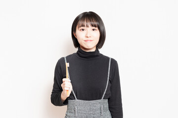 歯ブラシを持って見せている若い女性