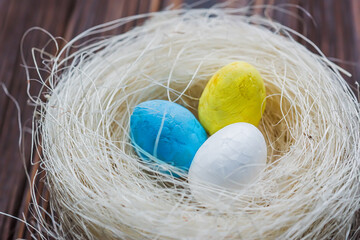 Two eggs of the color of the Ukrainian flag are yellow and blue and a white egg in the nest. The concept of an abandoned home of Ukraine for the Easter holiday.