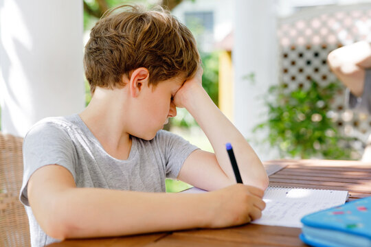 Hard-working Sad School Kid Boy Making Homework During Quarantine Time From Corona Pandemic Disease. Upset Tired Child On Home Schooling In Coronavirus Covid Time, Schools Closed.