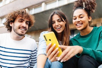 University student friends using mobile phone together to share content on social media