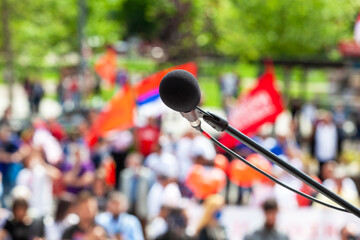 Protest, public demonstration or pension reform strike, focus on microphone, blurred crowd of...