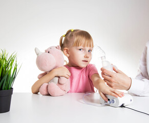 A little girl 5 years old in a pink T-shirt breathes into a nebulizer for lung disease. Treatment of bronchitis with inhalation, pharyngitis