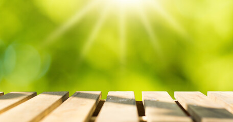 Wooden table top with natural green blurred background or various leaves, fresh bright sunlight, product empty concept.