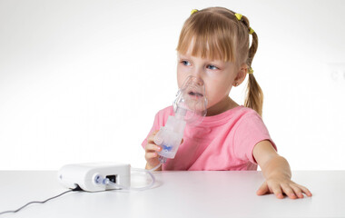 Beautiful little caucasian girl breathing into an inhaler for asthma and pneumonia at home....