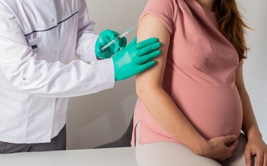 The doctor makes a revaccination of a pregnant girl against coronavirus and influenza. Prophylaxis