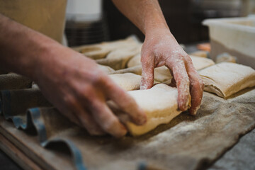 Naklejka premium Baker man placing bread dough on couche cloth to rest. Artisan bakery.