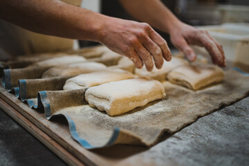 Anonymous baker man manipulating bread dough in handmade bakery
