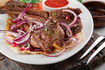 Grilled lamb rack served with vegetables and sauce on a white plate, lamb square meat dish. Close up