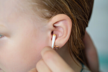 Cleaning a child's ear with a cotton swab from contamination of the ear drum and ear canal. Earwax...