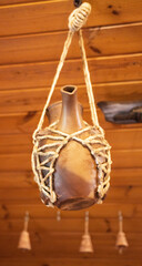 A ceramic jug with a spout suspended on a rope. Ceramic and clay dishes. Decor