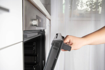 A man opens a modern oven door with child protection function. Oven with pizza mode function and 3d hot air