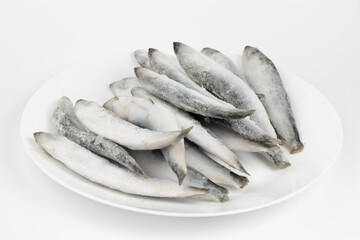 Frozen herring fish on a white plate.
