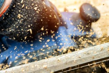 A man works with an electric tool with an electric planer, cleans old wood. Industry, close-up