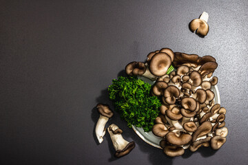 Delicious organic oyster mushrooms with fresh parsley. Source of beta glucan, black stone background