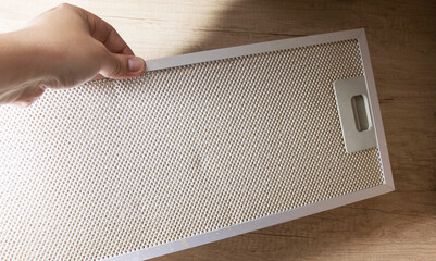 Modern kitchen hood with grease filter for air purification. Replacing the grease filter and...