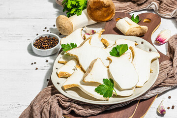 Fresh Pleurotus eryngii mushrooms on wooden background. Raw king oyster eringi with spices and herbs