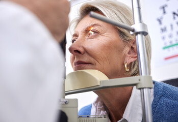 Eye exam, vision or laser test for a woman with a machine at optometry consultation for retina problem. Senior, patient or mature client with medical health insurance checking eyesight at optician