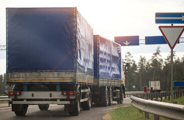 Naklejka premium A truck with a blue semi-trailer is transporting humanitarian aid on its way to another country, industry