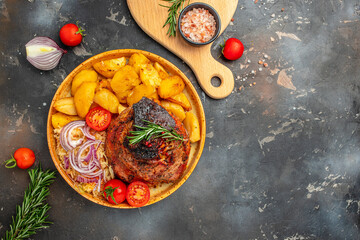 Fototapeta na wymiar Fried Pork Knuckle serve with potatoes, tomato on a dark background, banner, menu, recipe place for text, top view