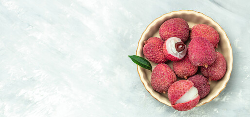 Ripe lychee. Exotic asian fruits in bowl on plate on a light background, Long banner format. top view