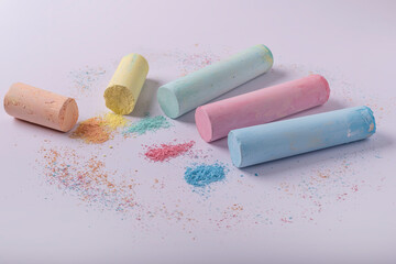 Cylindrical colored chalks, partially crumbled, on a white background