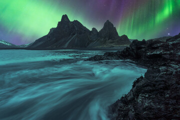 Picturesque view of black sand beach under sky with polar light