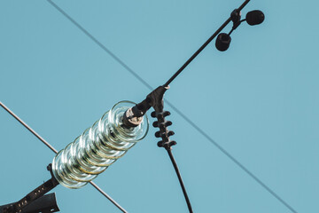 Glass insulators on high voltage electric transmission line close-up details with blue sky background