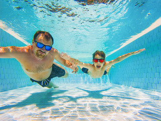 fater and son diving in the swimming pool. Family fun on vacation.