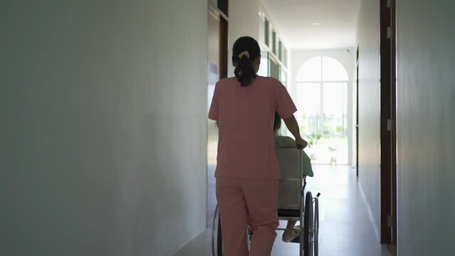 Old elderly disabled Asian patient or pensioner and a nurse using wheelchair to practice to walk in nursing home in hospital. Senior people lifestyle activity recreation. Health care physical therapy