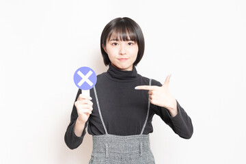 NGのプレートを見せている若い女性