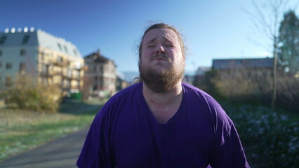 A fat young man taking a break from run. One overweight person recovering from exercising outdoors. Motivational discpline back into shape concept. Guy resting