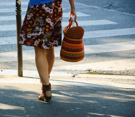 Woman wearing floral skirt and with shopping basket in hand crossing Parisian street. Paris, France. Springtime mood in air.