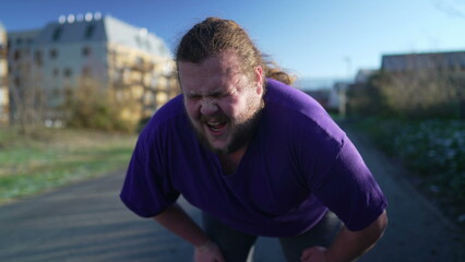 A fat young man taking a break from run. One overweight person recovering from exercising outdoors. Motivational discpline back into shape concept. Guy resting