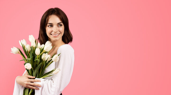 Smiling young european female with bouquet of tulips, enjoy lifestyle and rejoice in spring holiday