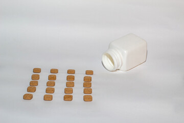 Grupo de medicamentos colocadas en fila una detrás de otra saliendo del bote sobre un fondo blanco.