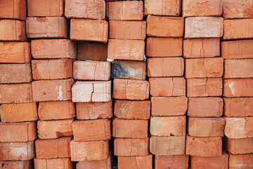 Obraz premium Stack of bricks close up. Process of house building and building materials concept. Red bricks for laying at construction site. Brick wallpaper pattern