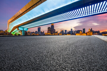 Asphalt road and bridge with city skyline at sunset in Shanghai, China.