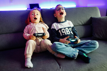 Naklejka premium The boy Danya and his younger sister Emilia play on the console.