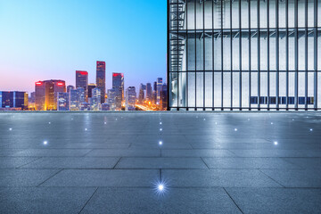 Empty square floor and city skyline with modern building at night in Beijing, China.